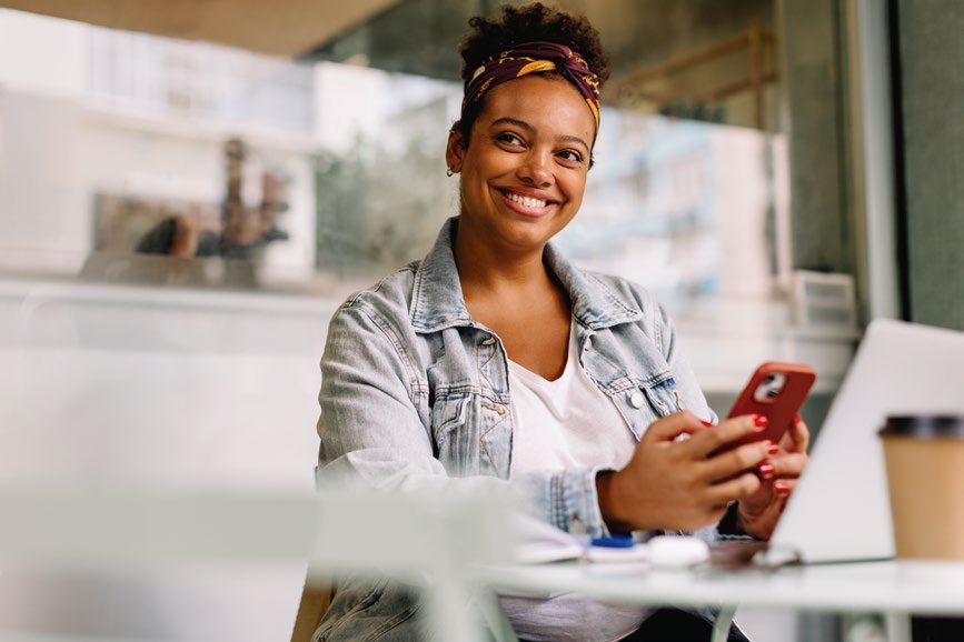 Mulher sorrindo enquanto usa o celular